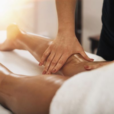 Anti cellulite massage. Masseuse massaging a calf area of a female leg to reduce cellulite